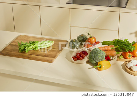 Top view of fresh vegetables such as cauliflower, bell peppers, tomatoes, carrots and pumpkin. Celery placed on a wooden cutting board. Light shines through the window casting shadows on the objects. Top view of fresh vegetables such as cauliflower, bell peppers, tomatoes, carrots and pumpkin. Celery placed on a wooden cutting board. Light shines through the window casting shadows on the objects. 125313047