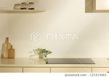 Modern and minimalist kitchen counter. Flat black electric stove with glossy surface. Glass jars of ingredients placed on wooden shelves hanging on the wall. Used for interior advertising photos. 125313063