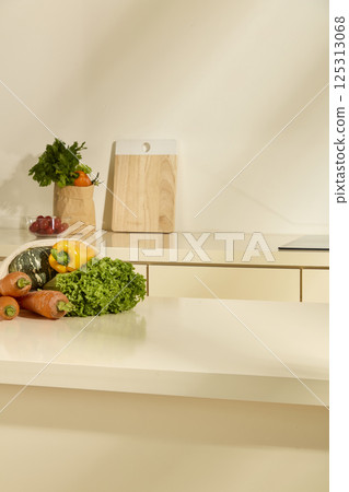 A bag filled with fresh organic vegetables such as carrots, yellow bell peppers, zucchini and lettuce sits on a corner of the table. Light shines in from the right. Modern, minimalist kitchen. A bag filled with fresh organic vegetables such as carrots, yellow bell peppers, zucchini and lettuce sits on a corner of the table. Light shines in from the right. Modern, minimalist kitchen. 125313068