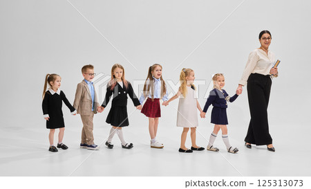 School children smiling and bonding in group portrait with books and teacher against white background. Concept of academic, study School children smiling and bonding in group portrait with books and teacher against white background. Concept of academic, study 125313073