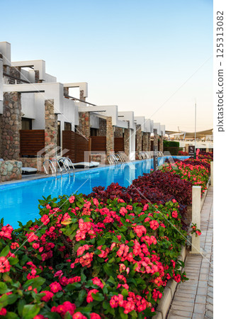 Luxurious resort pool surrounded by vibrant flowers in a serene setting at sunset Luxurious resort pool surrounded by vibrant flowers in a serene setting at sunset 125313082