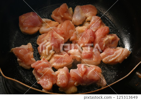 Juicy chicken thighs fried in a frying pan 125313649