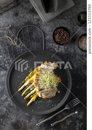 Sliced pork loin with grilled asparagus and creamy sauce on black plate Sliced pork loin with grilled asparagus and creamy sauce on black plate 125313760