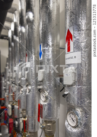 Heating and cooling system pipes running along wall in boiler room Heating and cooling system pipes running along wall in boiler room 125313778
