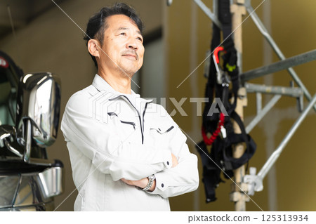 一名中年男子在卡車前擺姿勢的施工影像 一名中年男子在卡車前擺姿勢的施工影像 125313934