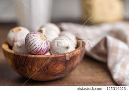 Solo glove garlic bulbs in bowl on wooden table. Solo glove garlic bulbs in bowl on wooden table. 125314023