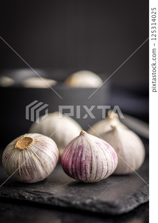Solo glove garlic bulbs on black table. Solo glove garlic bulbs on black table. 125314025