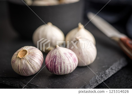 Solo glove garlic bulbs on black table. Solo glove garlic bulbs on black table. 125314026