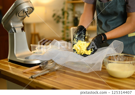 Hands preparing fresh butter on cheesecloth with bowl of buttermilk nearby Hands preparing fresh butter on cheesecloth with bowl of buttermilk nearby 125314407