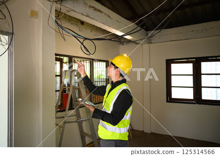 Male construction supervisor examining electrical cables at renovation site 125314566