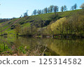 River bank in spring. The calm flow of the river surrounded by spring nature.  125314582