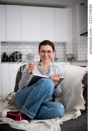 Happy Young Woman Reading And Writing Notes With Pen In Book Happy Young Woman Reading And Writing Notes With Pen In Book 125314686