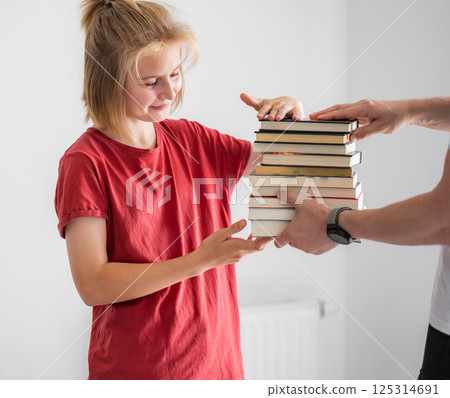 Father Gives A Stack Of School Books For Studying To Cute Little Daughter Father Gives A Stack Of School Books For Studying To Cute Little Daughter 125314691