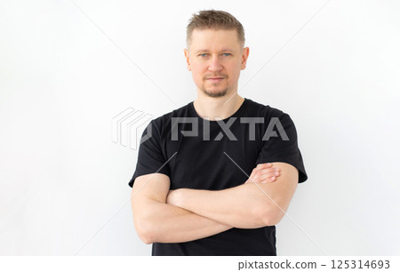 Handsome Man In A Black T-Shirt With Crossed Hands Isolated On A White Background Handsome Man In A Black T-Shirt With Crossed Hands Isolated On A White Background 125314693