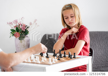 Thoughtful, Cute Little Girl Playing Chess At Home, Training With Father 125314706