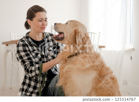 Cute Girl Petting An Adorable Golden Retriever In A Bright Room Cute Girl Petting An Adorable Golden Retriever In A Bright Room 125314767