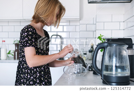 Cute Little Girl Brewing Black Tea For Breakfast In The Kitchen 125314772