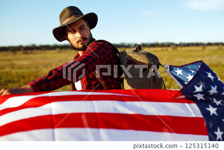 4th of July. American Flag.Patriotic holiday. Traveler with the flag of America. Beautiful sunset light. American style. 4th of July. American Flag.Patriotic holiday. Traveler with the flag of America. Beautiful sunset light. American style. 125315140