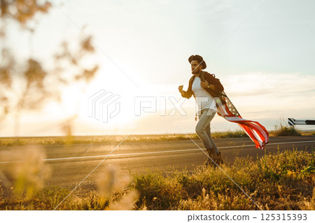 4th of July. American Flag.Patriotic holiday. Traveler with the flag of America. Beautiful sunset light. American style. 125315393