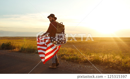 4th of July. American Flag.Patriotic holiday. Traveler with the flag of America. Beautiful sunset light. American style. 125315397
