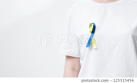 Symbolizing World Down Syndrome Day. A person wearing a white t-shirt with a yellow and blue awareness ribbon Symbolizing World Down Syndrome Day. A person wearing a white t-shirt with a yellow and blue awareness ribbon 125315454