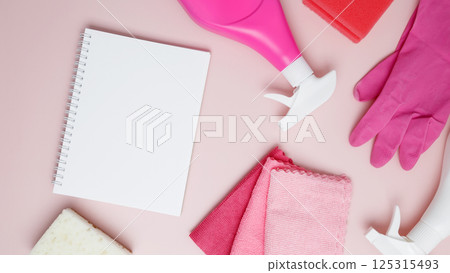 Household cleaning and hygiene concept. Mock up notebook. Pink cleaning supplies including rubber gloves, spray bottle, microfiber cloths 125315493
