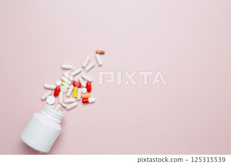 White bottle container with colorful medication capsules and tablets. Concept of healthcare and medicine 125315539