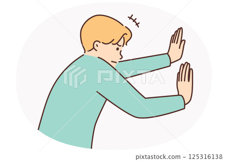 Man tensely pushes invisible wall with hands or sets himself goal of opening secret passage 125316138