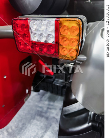 Detailed view of tractor tail light highlighting functionality and design in agricultural setting 125316313