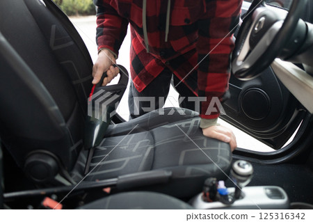 Cleaning the interior of the car with a vehicle vacuum cleaner. 125316342