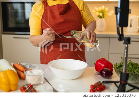 Senior Woman Adding Vinegar to a Bowl While Cooking in the Kitchen Senior Woman Adding Vinegar to a Bowl While Cooking in the Kitchen 125316376