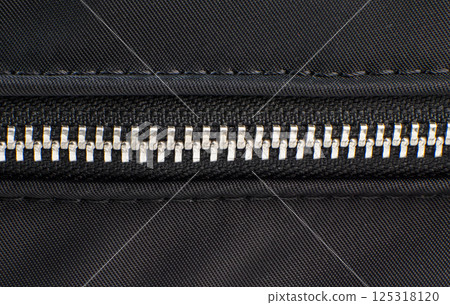 Detailed view shows a metal zipper on black textile surface 125318120