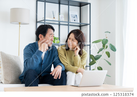 A middle-aged couple using a computer in the living room A middle-aged couple using a computer in the living room 125318374