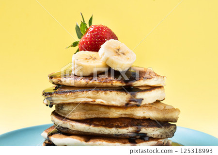 Pancakes with chocolate, strawberry and banana on yellow background 125318993