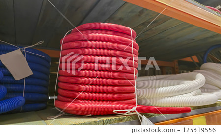 A plastic corrugated hose wound on a reel is displayed for sale on a store shelf 125319556