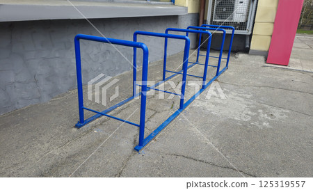 Metal bicycle parking near supermarket. Parking made of blue pipes. Metal bicycle parking near supermarket. Parking made of blue pipes. 125319557