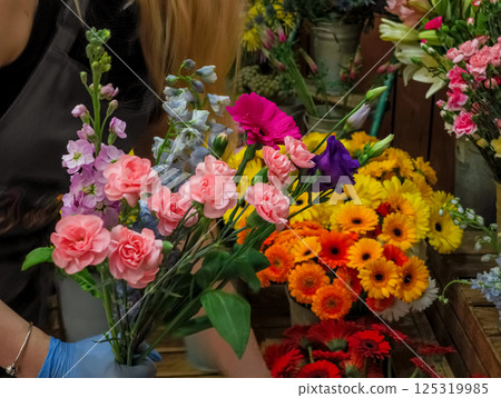Florist arranging pink carnations and colorful flowers in bouquet 125319985