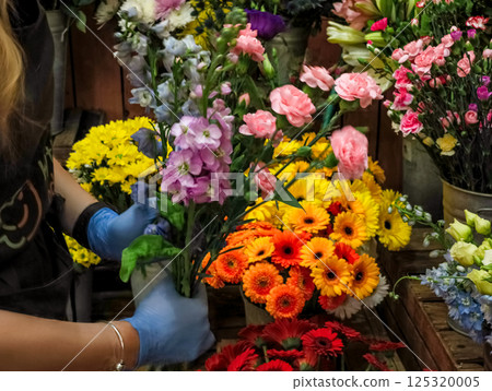 Florist arranging colorful flowers in a flower shop Florist arranging colorful flowers in a flower shop 125320005