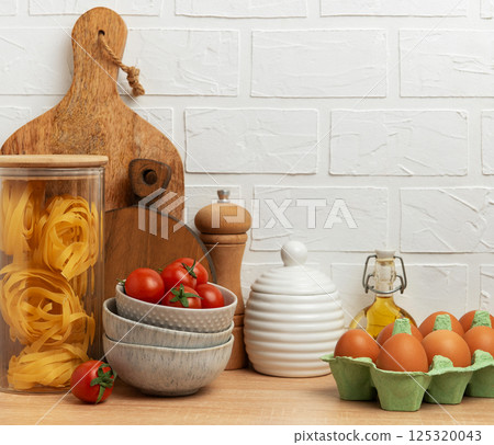 Italian food, cherry tomatoes, pasta, eggs and olive oil creating cozy kitchen scene 125320043