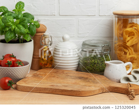 Empty wooden cutting board with various ingredients and utensils displayed on kitchen countertop Empty wooden cutting board with various ingredients and utensils displayed on kitchen countertop 125320045