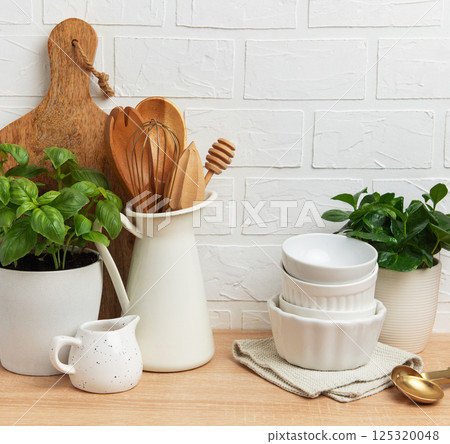 Kitchen utensils and plants creating cozy atmosphere on wooden countertop 125320048