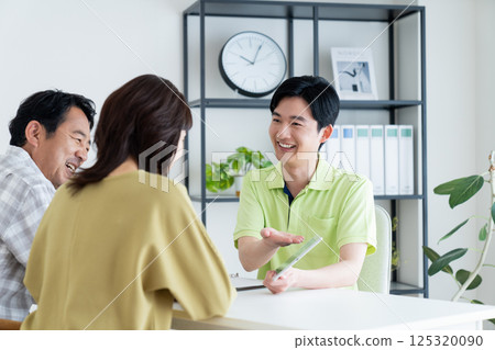 A care manager explaining a care plan to a middle-aged couple 125320090