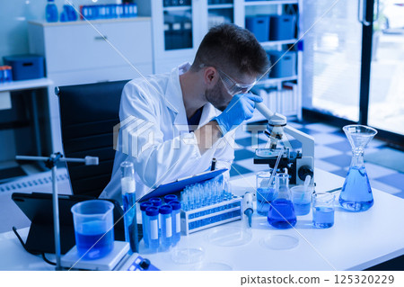 Chemist scientist holding test tube conducting experiment in laboratory with equipment. Chemist scientist holding test tube conducting experiment in laboratory with equipment. 125320229