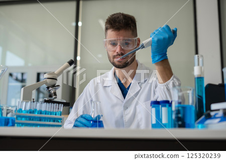 Chemist scientist holding test tube conducting experiment in laboratory with equipment. 125320239