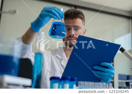 Chemist scientist holding test tube conducting experiment in laboratory with equipment. Chemist scientist holding test tube conducting experiment in laboratory with equipment. 125320245