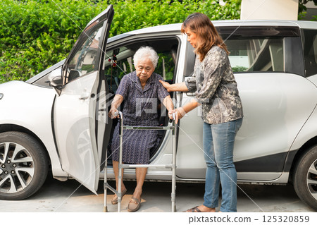 Caregiver help Asian elderly woman disability patient get in her car. 125320859