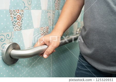 Asian elderly woman patient use handrail safety in toilet support rail in bathroom. 125320931