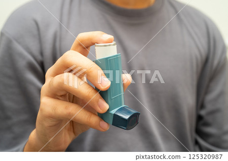 Asthma and chronic obstructive pulmonary disease COPD, Asian young man using metered dose inhaler MDI. 125320987