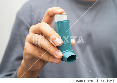 Asthma and chronic obstructive pulmonary disease COPD, Asian young man using metered dose inhaler MDI. 125321061