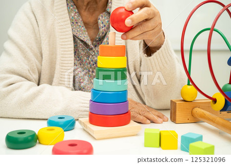 Asian elderly woman playing enhancing skill board game. 125321096
